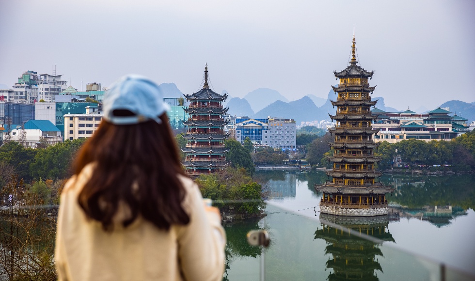 在中国桂林市中心，年轻的女子一边喝着咖啡，一边看着宝塔_副本