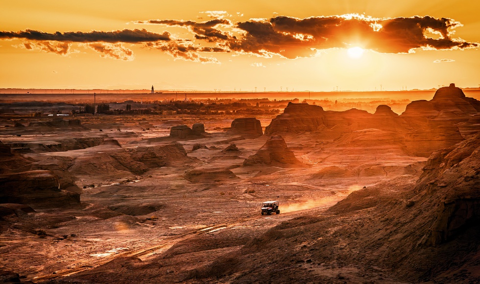 中国新疆克拉玛依，夕阳下世界鬼城沙漠地带行驶的汽车_副本